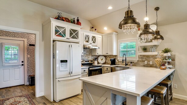 A modern kitchen with white cabinetry, a large island, and pendant lighting. - Backyard Bungalow w/ Pool & Country Views (Argyle)