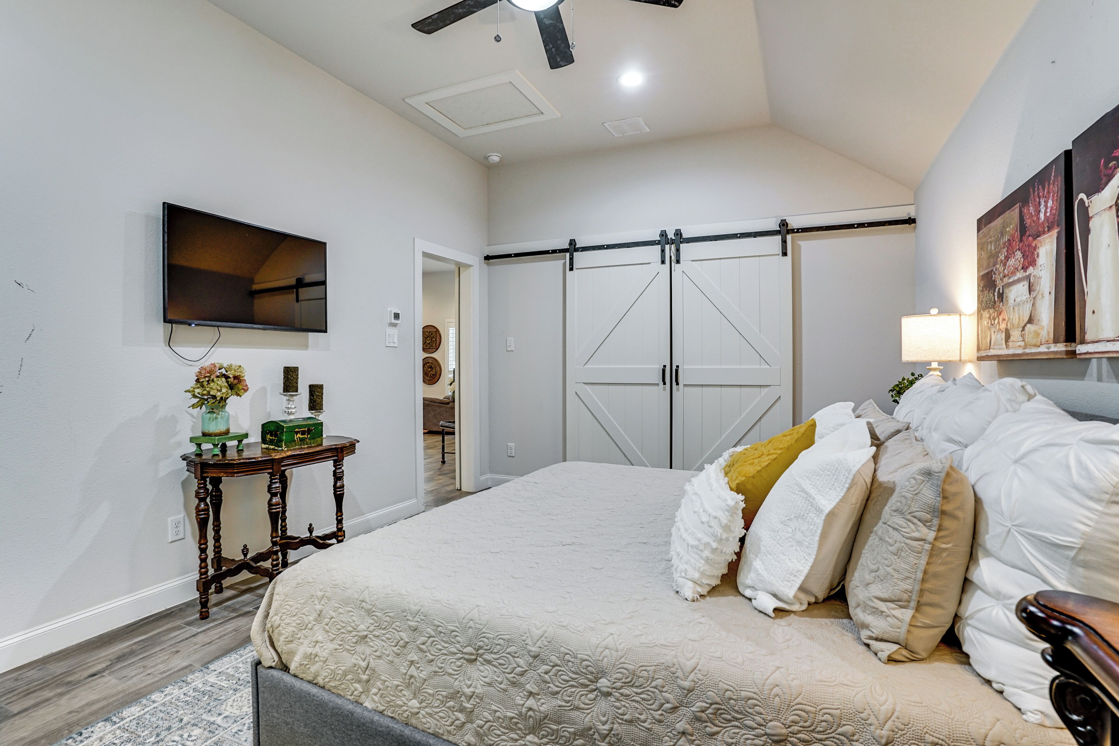 A bedroom with a bed, a television, a sliding door closet, and a small table with a vase.