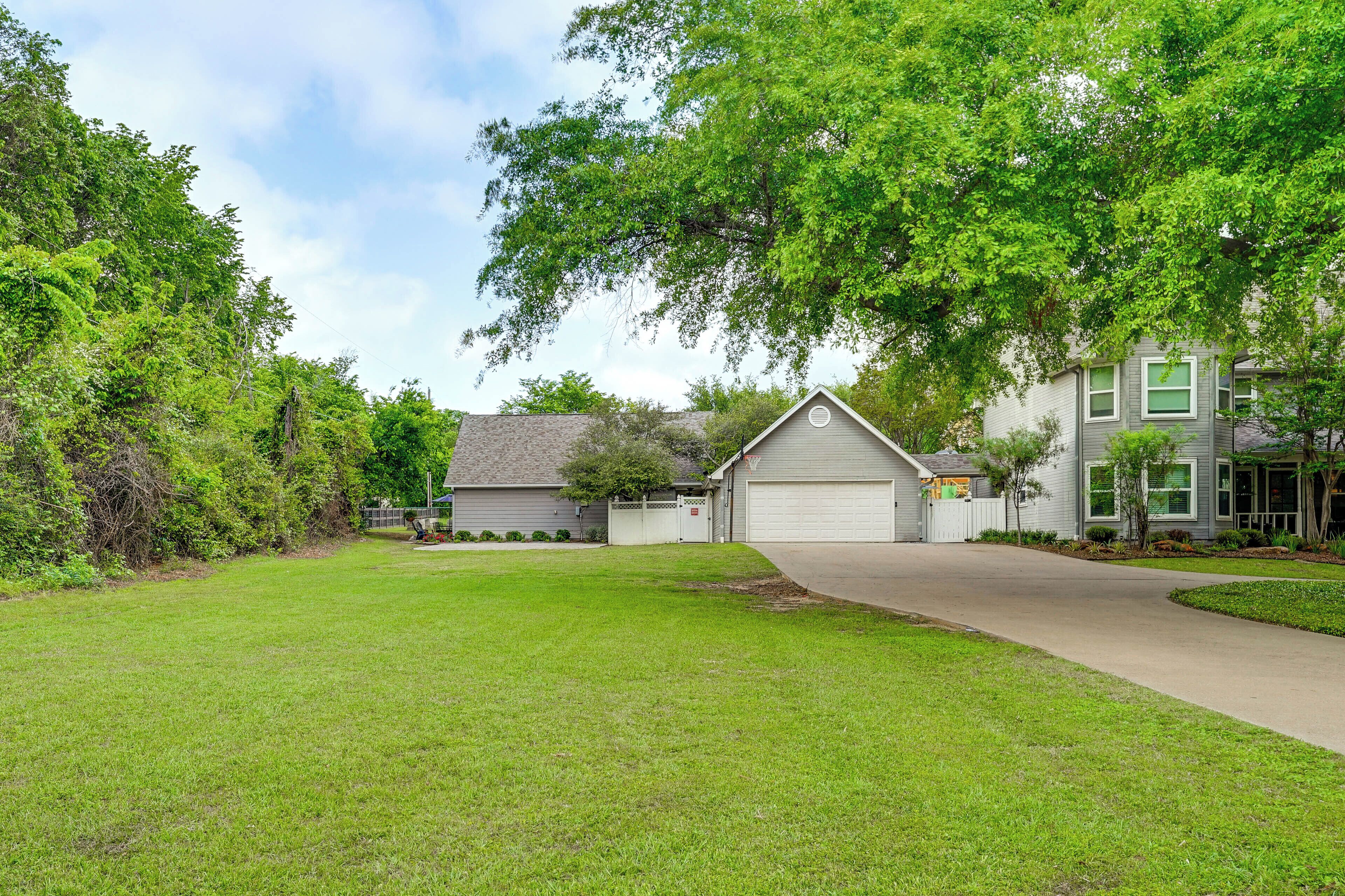 A residential area with a well-maintained lawn, a driveway leading to a garage, and houses with front yards.