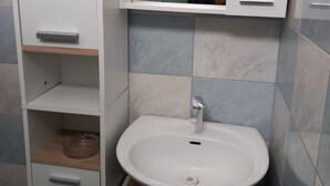 Een badkamer met een witte wastafel, spiegel en kastjes.
