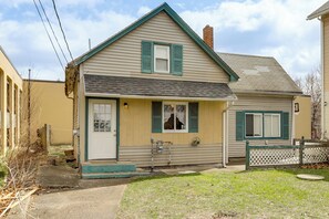 A two-story house with a front porch, a visible chimney, and a fenced yard.