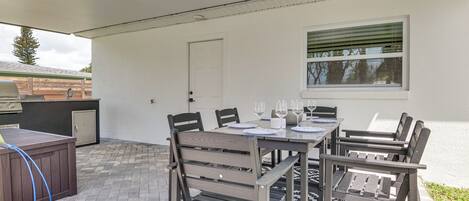 Un patio al aire libre con una mesa lista para cuatro, una parrilla y un área cubierta.