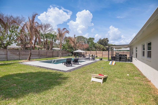 A backyard with a swimming pool, patio furniture, and a wooden deck.