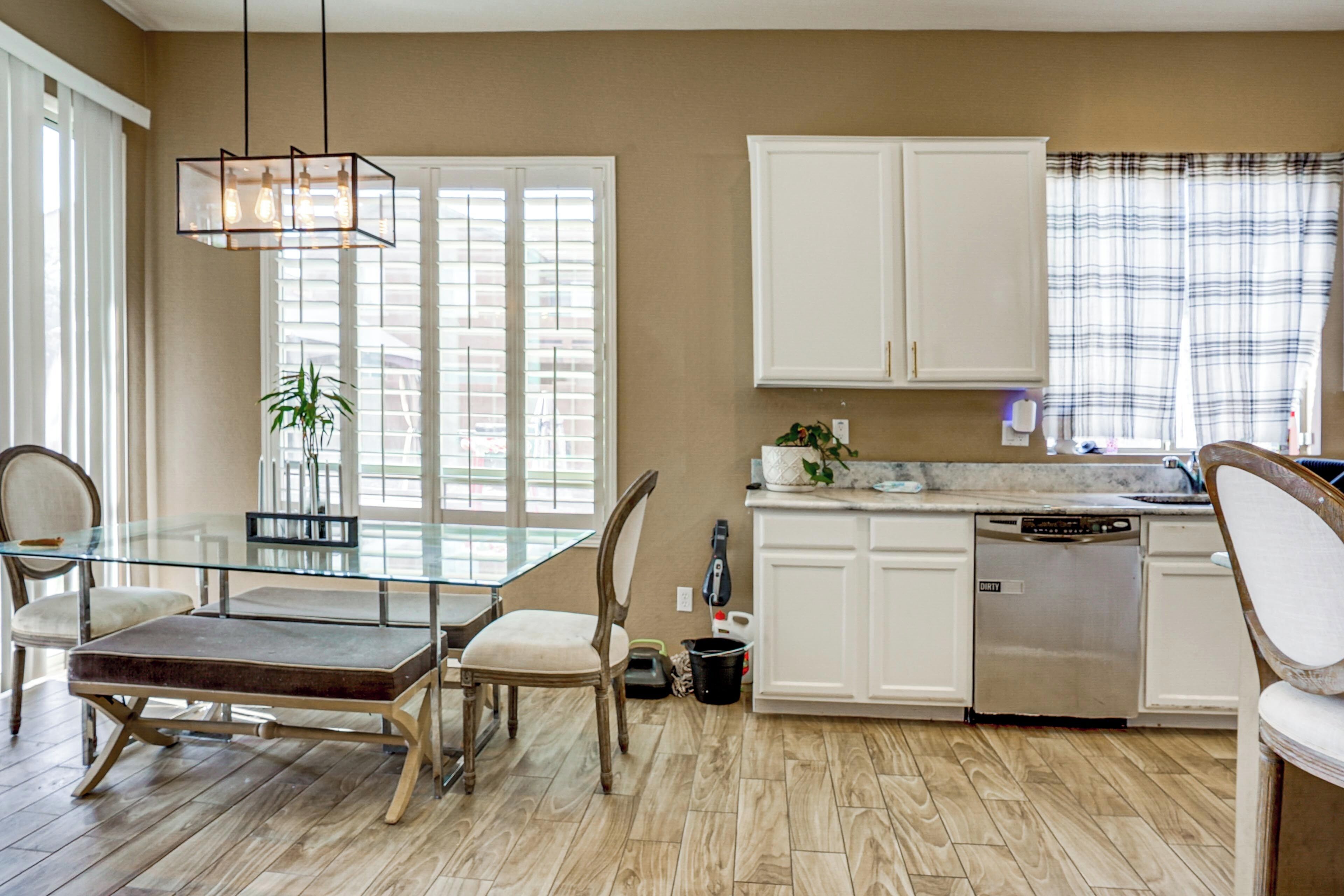 A modern kitchen with a glass dining table, white cabinetry, and a dishwasher.