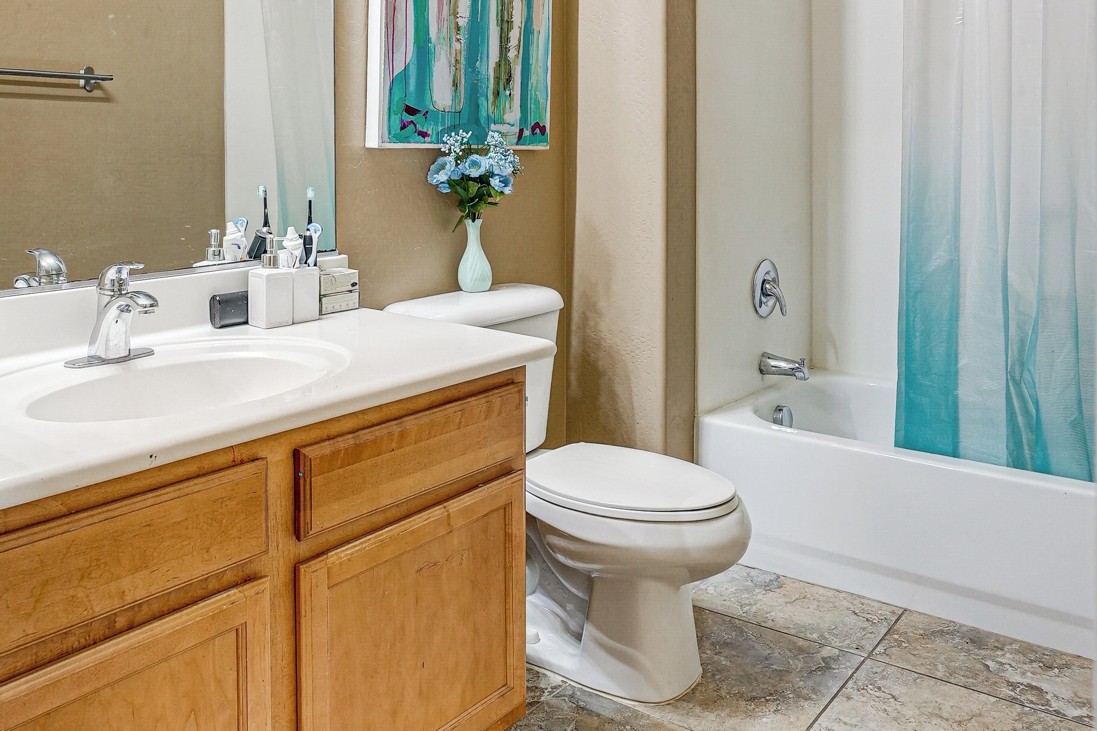A bathroom with a white sink, wooden vanity, a toilet, and a bathtub.