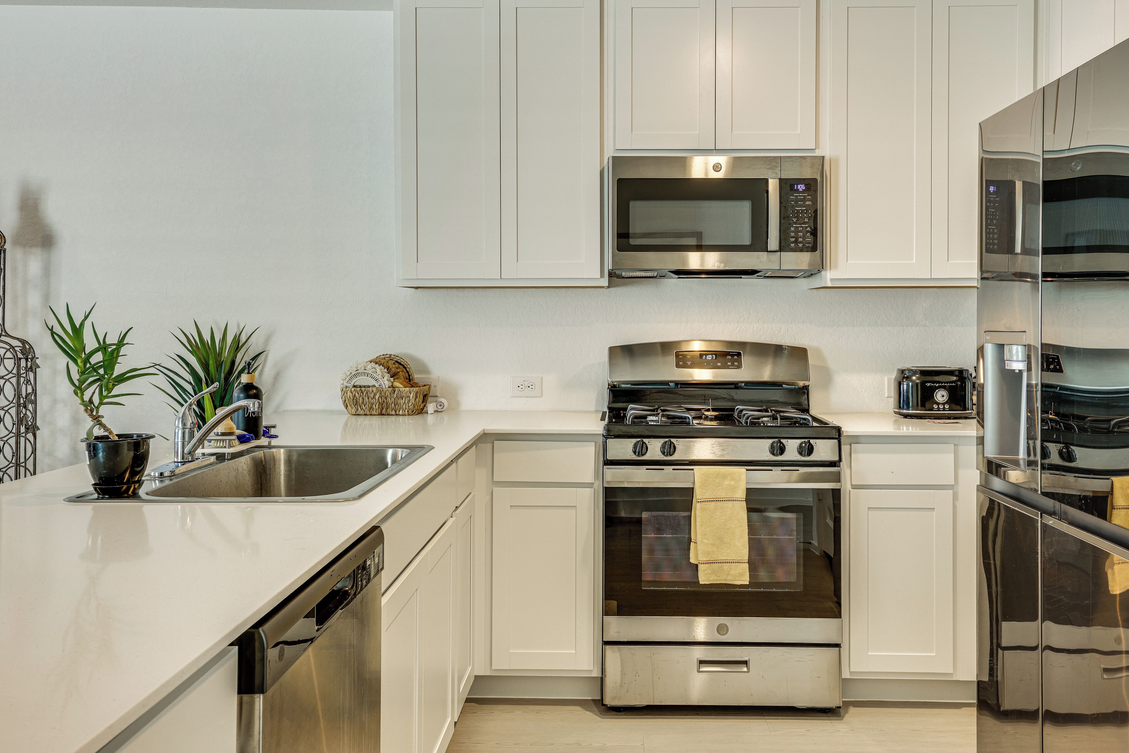 Una cocina moderna con electrodomésticos de acero inoxidable, lavavajillas y un lavamanos.