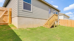 Une maison à deux étages dotée d’une terrasse en bois et d’un petit escalier menant à la porte d’entrée.