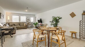 Un salon avec une table ronde en bois, des chaises, un canapé et un téléviseur.