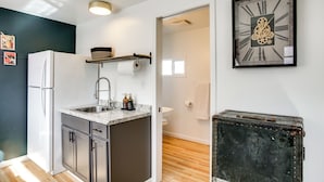 A modern kitchen with a refrigerator, sink, and countertop. There is a clock on the wall and a suitcase in the corner. - Unit 8: Our Largest & Highest-rated 1-br (Spokane)