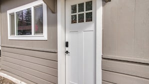 A white door with a glass panel, a window with a white frame, and siding on the house. - Unit 8: Our Largest & Highest-rated 1-br (Spokane)