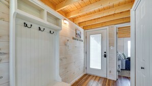 Ein Korridor mit Holzdielen, weißen Wänden und einer Tür zu einem Schlafzimmer.