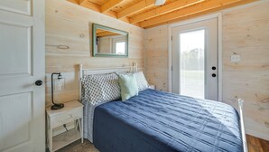 Ein Schlafzimmer mit Bett, Nachttisch, Lampe und einer Tür.