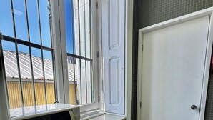 Una cucina con una finestra, un forno a microonde, pensili verdi e una porta bianca.