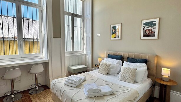 Una camera da letto con un letto grande, due comodini, una lampada a sospensione e due finestre.