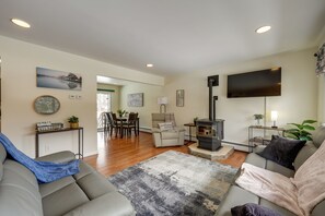 A living room with a sofa, a coffee table, a fireplace, a television, and a dining area in the background.