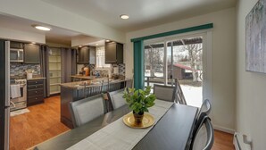 Une cuisine moderne avec des meubles de couleur sombre, un îlot central et un coin repas comprenant une table et des chaises.