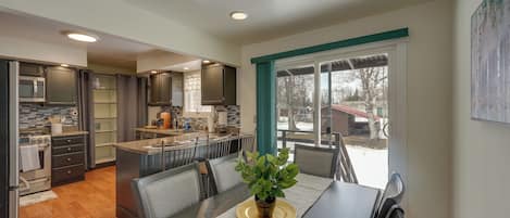 A modern kitchen with dark cabinets, a central island, and a dining area with a table and chairs.