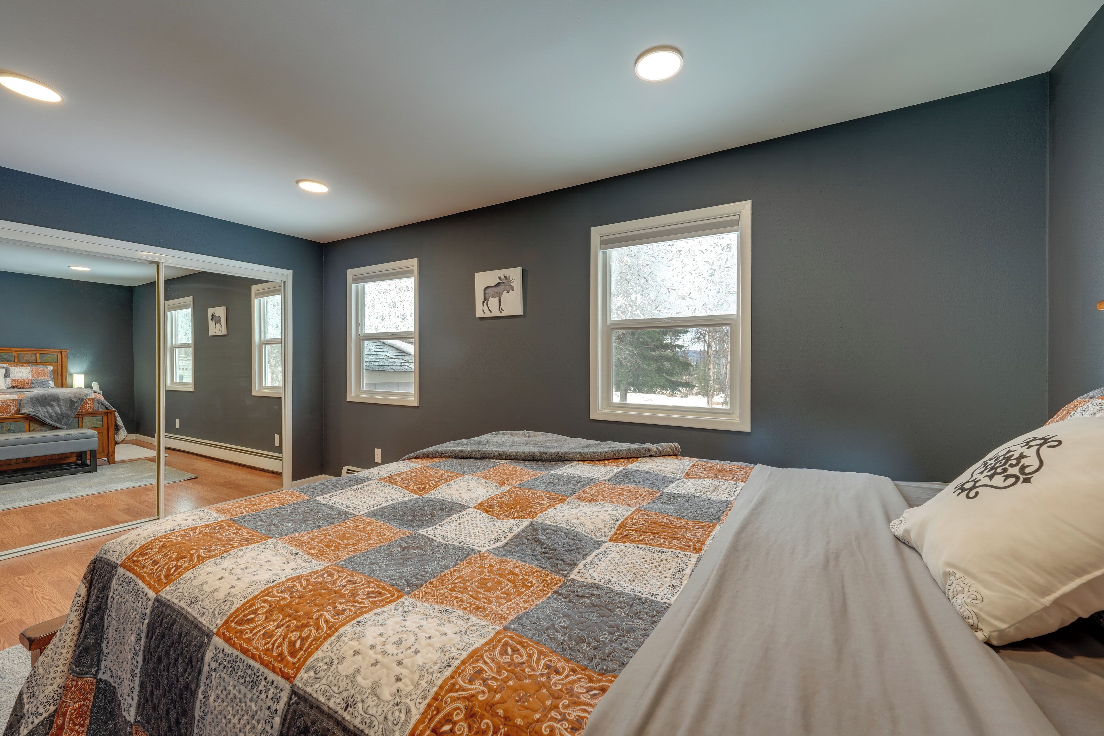 A bedroom with a large bed, a mirror, and a window.