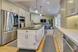 A modern kitchen with stainless steel appliances, a central island, and a seating area with a sofa and bar stools. - 1 Mi to Beach! 'carlsbad Retreat' w/ Serene Garden (Carlsbad)