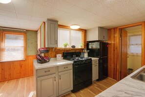Eine kleine Küche mit Holzwänden, einem schwarzen Herd und einem Kühlschrank.