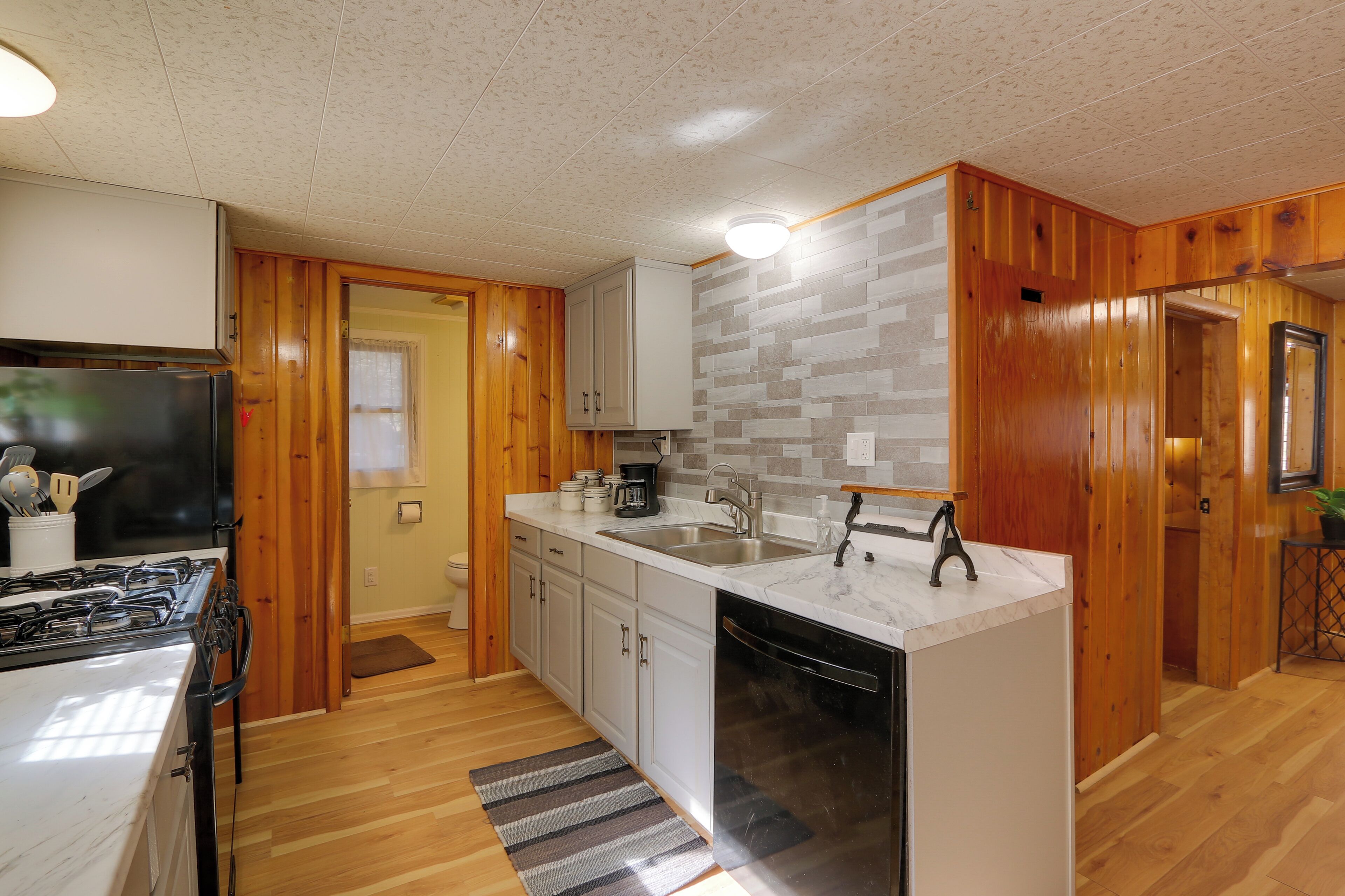 A compact kitchen with wooden cabinets, a white countertop, and a built-in dishwasher.