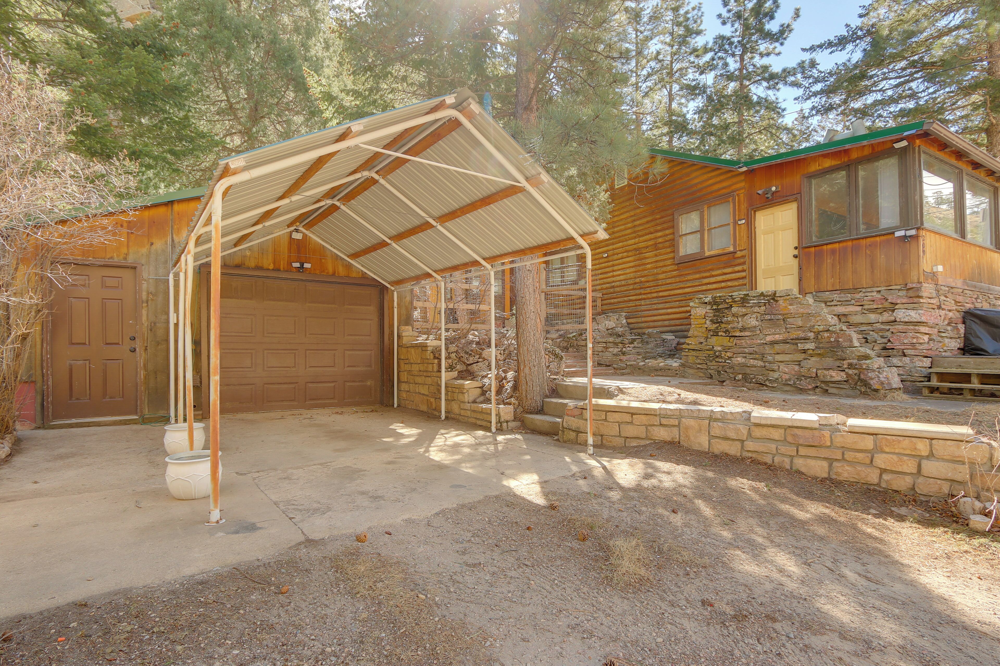 A cabin with a covered patio, a stone wall, and a garage.