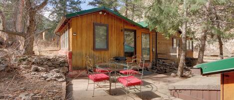 A wooden cabin with a patio area, including a table and chairs.