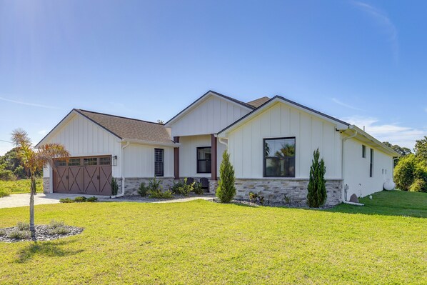 A two-story house with a garage, a stone foundation, and a well-maintained lawn. - 1 Mi to Boat Ramp! Lake Placid Home w/ Dock (Lake Placid)