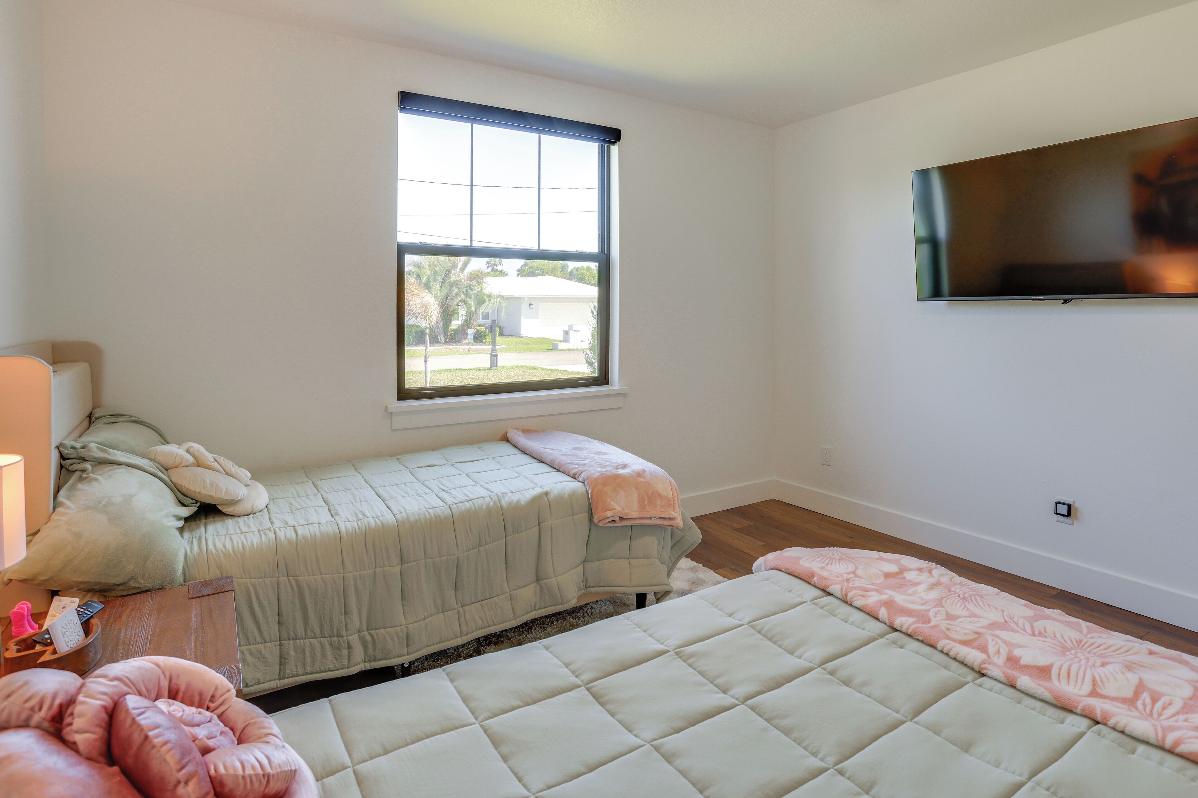 A bedroom with a bed, a window, a television, and a nightstand.