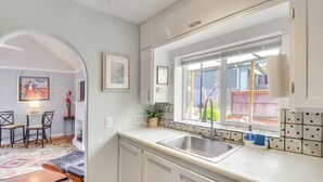 Una cocina con ventana, un fregadero y una zona de comedor con sillas y mesa.