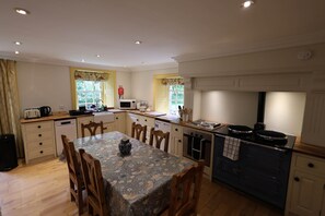A compact kitchen with a dining table, chairs, a microwave, a kettle, and a stove. - Forget Me Not - Craigengillan Estate (Dalmellington)