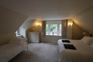 Ein Schlafzimmer mit zwei Betten, einem Schminktisch, einem Ventilator und einem Fenster mit Vorhängen.