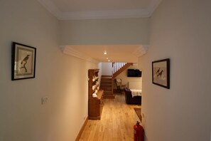 A hallway with wooden flooring, a staircase, and framed artwork on the walls. - Forget Me Not - Craigengillan Estate (Dalmellington)