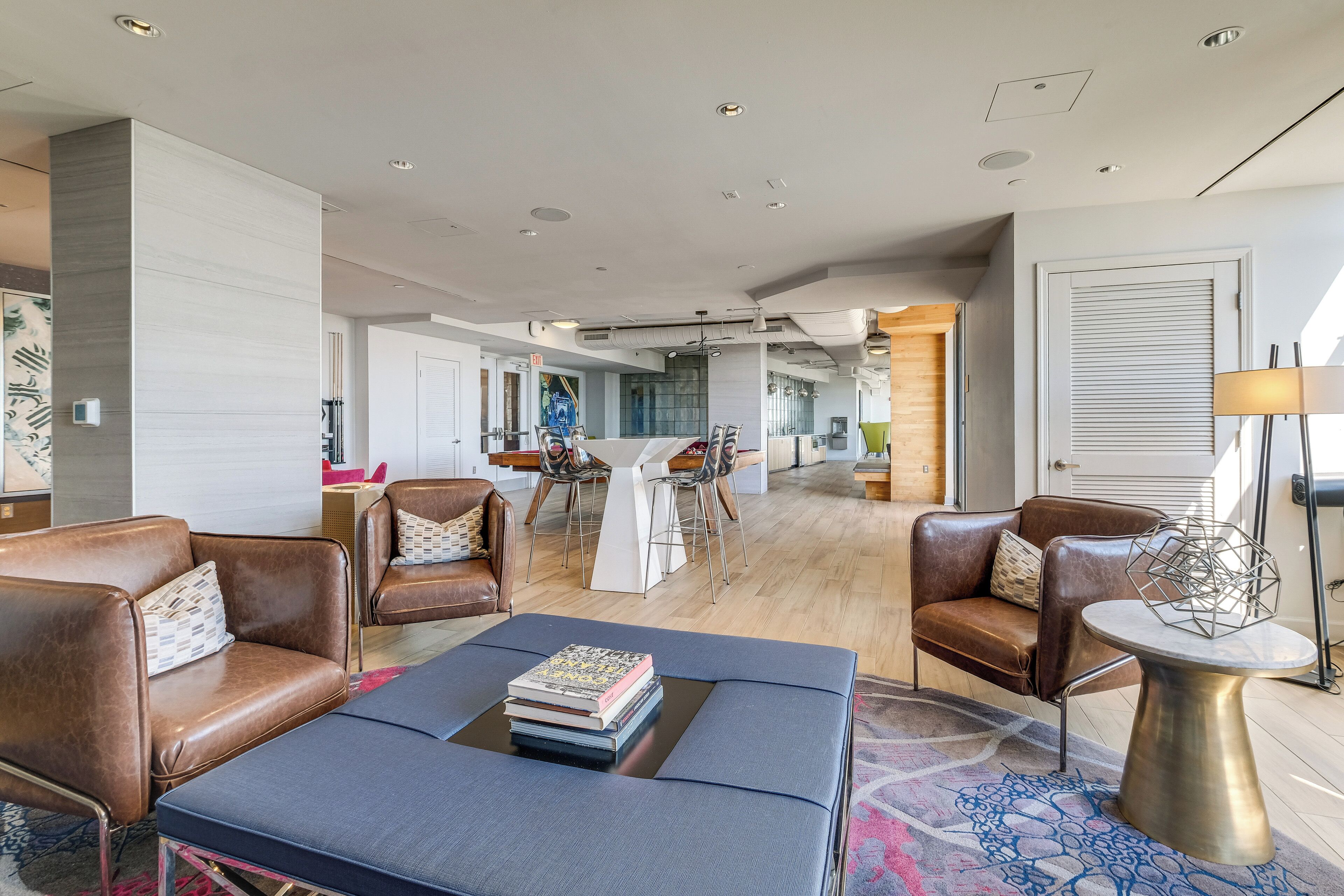 A modern living room with leather sofas, a coffee table, and a dining area with a white table and chairs.