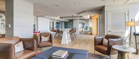 A modern living room with leather sofas, a coffee table, and a dining area with a white table and chairs.