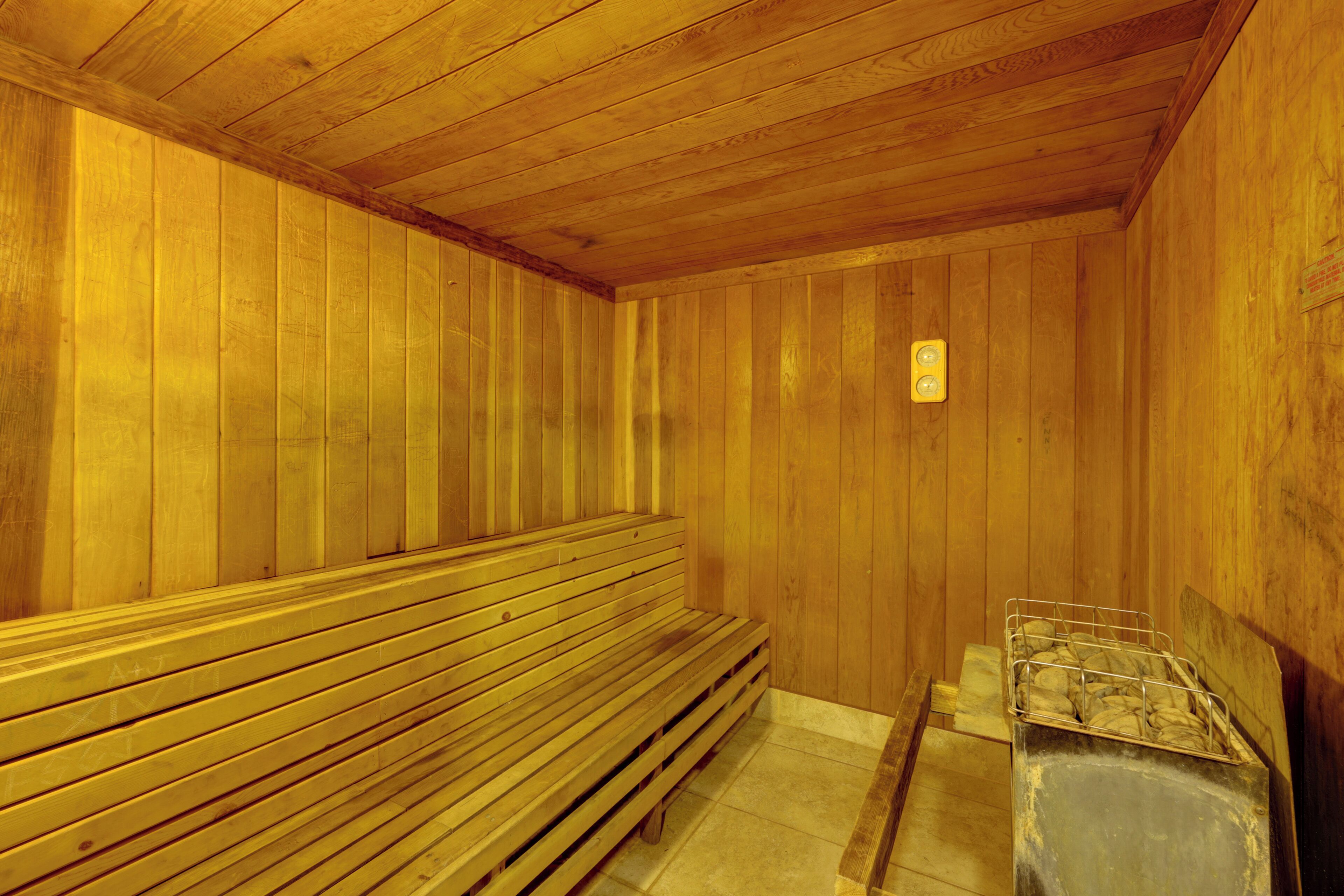 Un sauna de madera con bancos y un recipiente metálico.