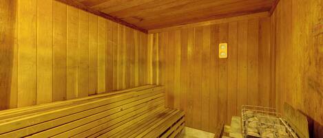Un sauna de madera con bancos y un recipiente metálico.