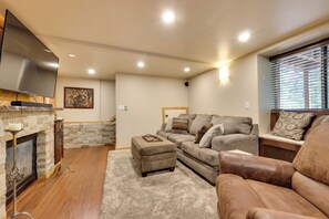 Una sala de estar con chimenea, televisor, sofá y sillón de cuero.