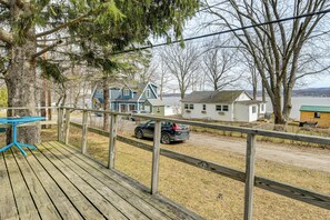 A wooden deck with a table, a fenced area, and houses in the background. - Steps to St Albans Bay! Basecamp w/ Grill (St. Albans)