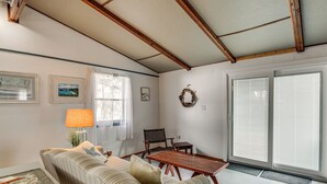 Una sala de estar con un sofá, una mesa de madera, una silla, una lámpara y una ventana con persianas.