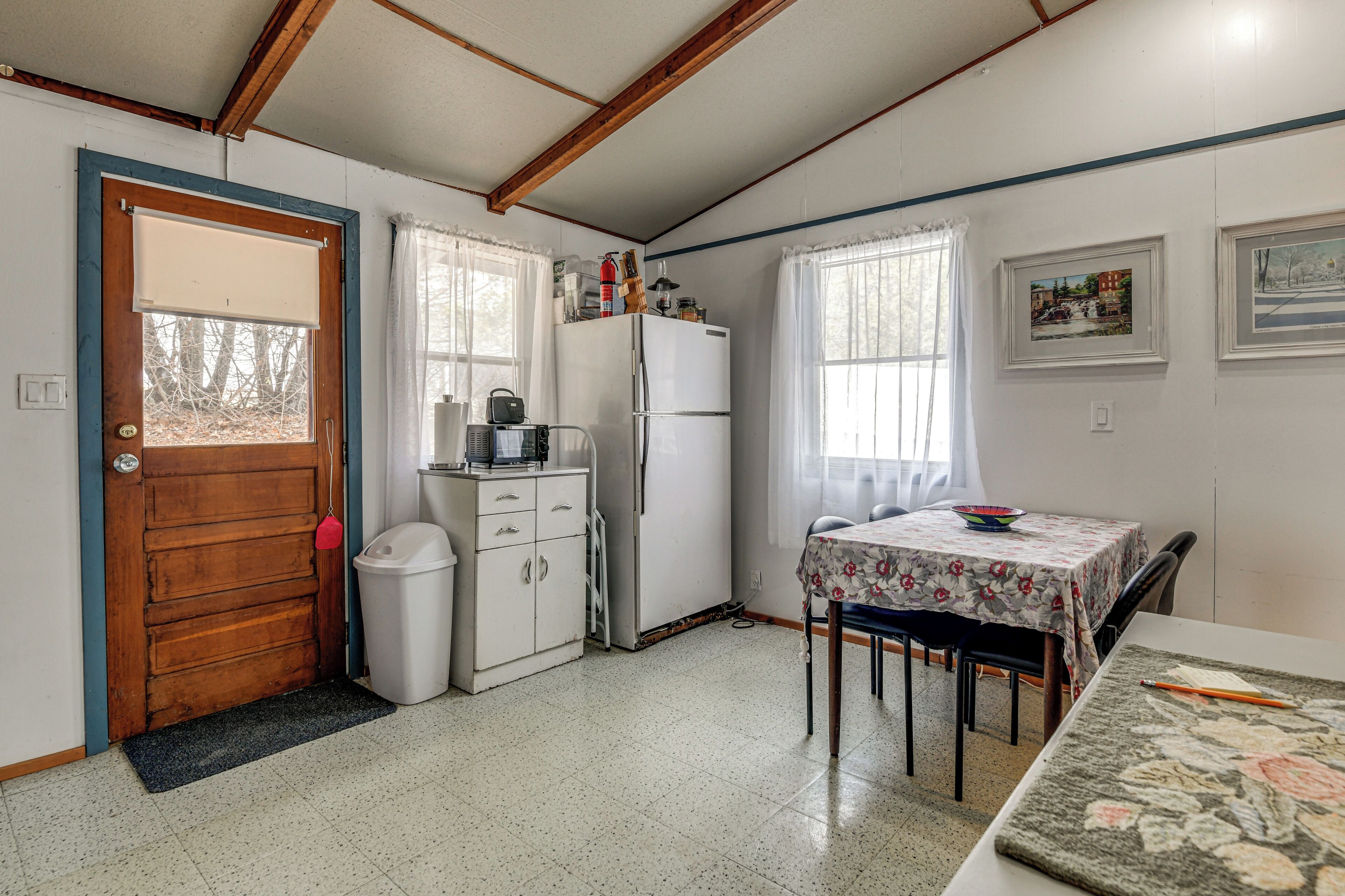 A compact kitchen with a refrigerator, a small sink, and a dining table with chairs.