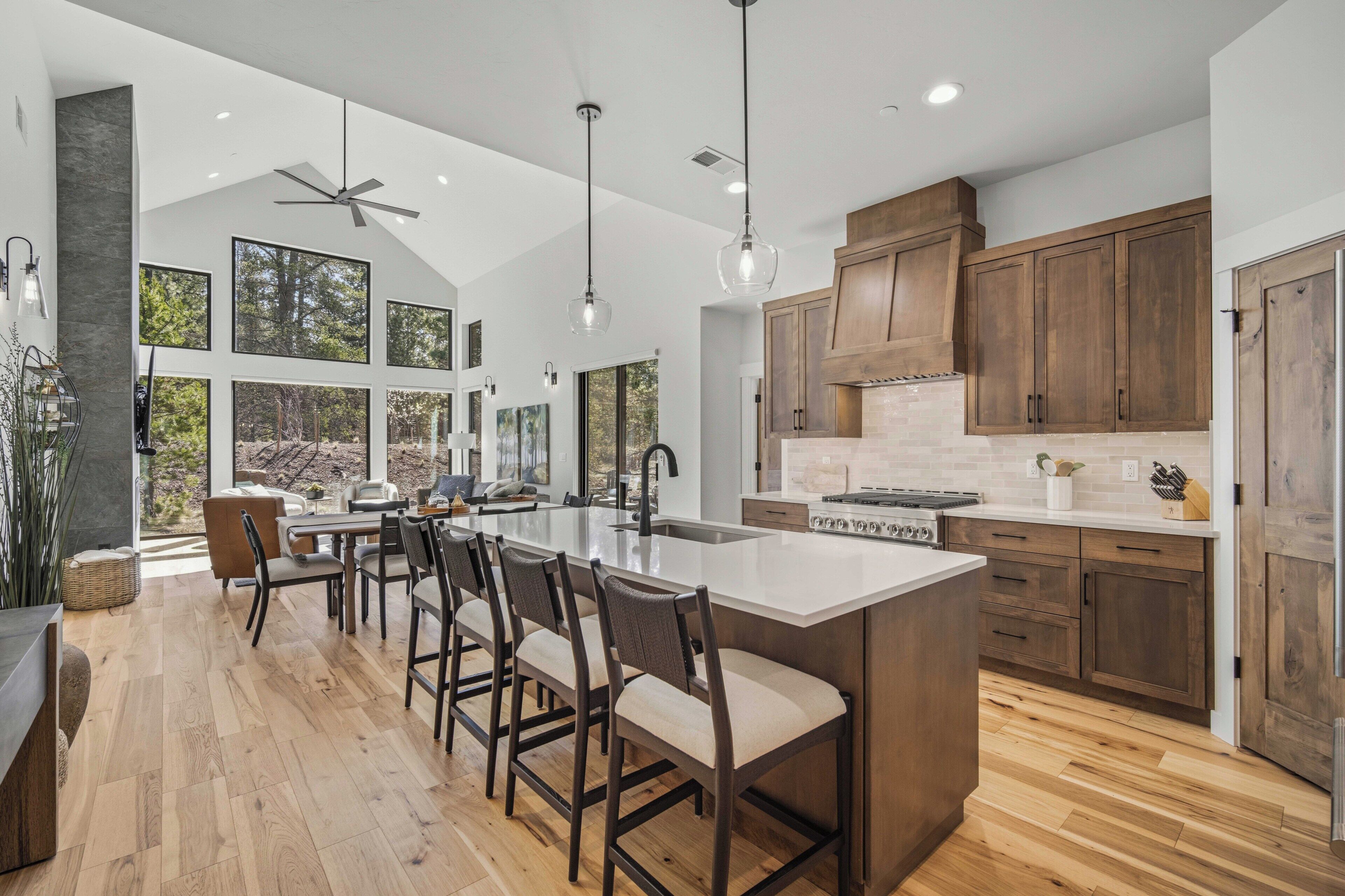 A modern kitchen with a large island, wooden cabinets, and a dining area with bar stools.