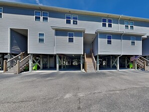 A multi-story building with a covered parking area and a staircase leading to the entrance. - Lazy Daze | Intercoastal Views + Pool Access (Surf City)