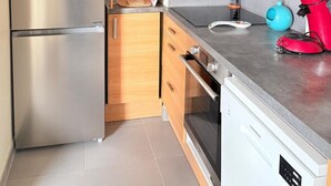 Une cuisine équipée d’appareils électroménagers en acier inoxydable, de meubles en bois, d’un four à micro-ondes et d’un lave-vaisselle.