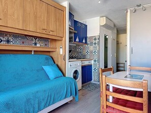 Une petite pièce comprenant un lit, un lave-linge, une petite table et une chaise.