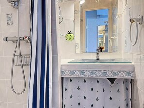 Une salle de bain avec une douche, un lavabo avec un plateau en verre et un miroir.
