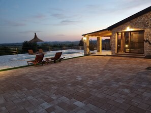 Une terrasse sur le toit avec une piscine, des chaises longues et un bâtiment en pierre doté d’une porte en verre.