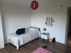 Un dormitorio con una cama, una mesita de noche, una lámpara, una botella de agua y un bolso.