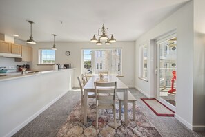 A modern kitchen with a dining area, large windows, and a view of the outside. - 421 - Sand-tastic Adventures Await - Oceanview (Westport)