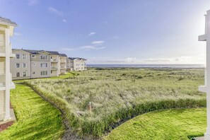 A residential area with multi-story buildings, a grassy field, and a clear sky. - 421 - Sand-tastic Adventures Await - Oceanview (Westport)